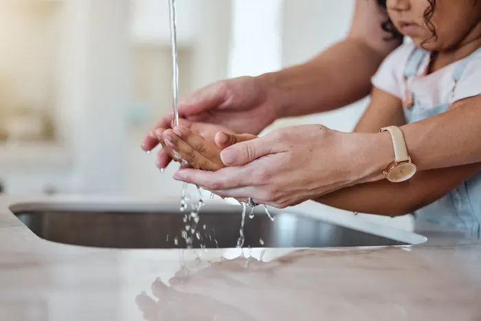 A parent and child holding their hands under running tap water